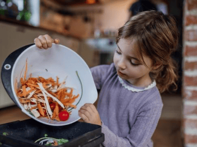 Child discards food scraps into a compost bin