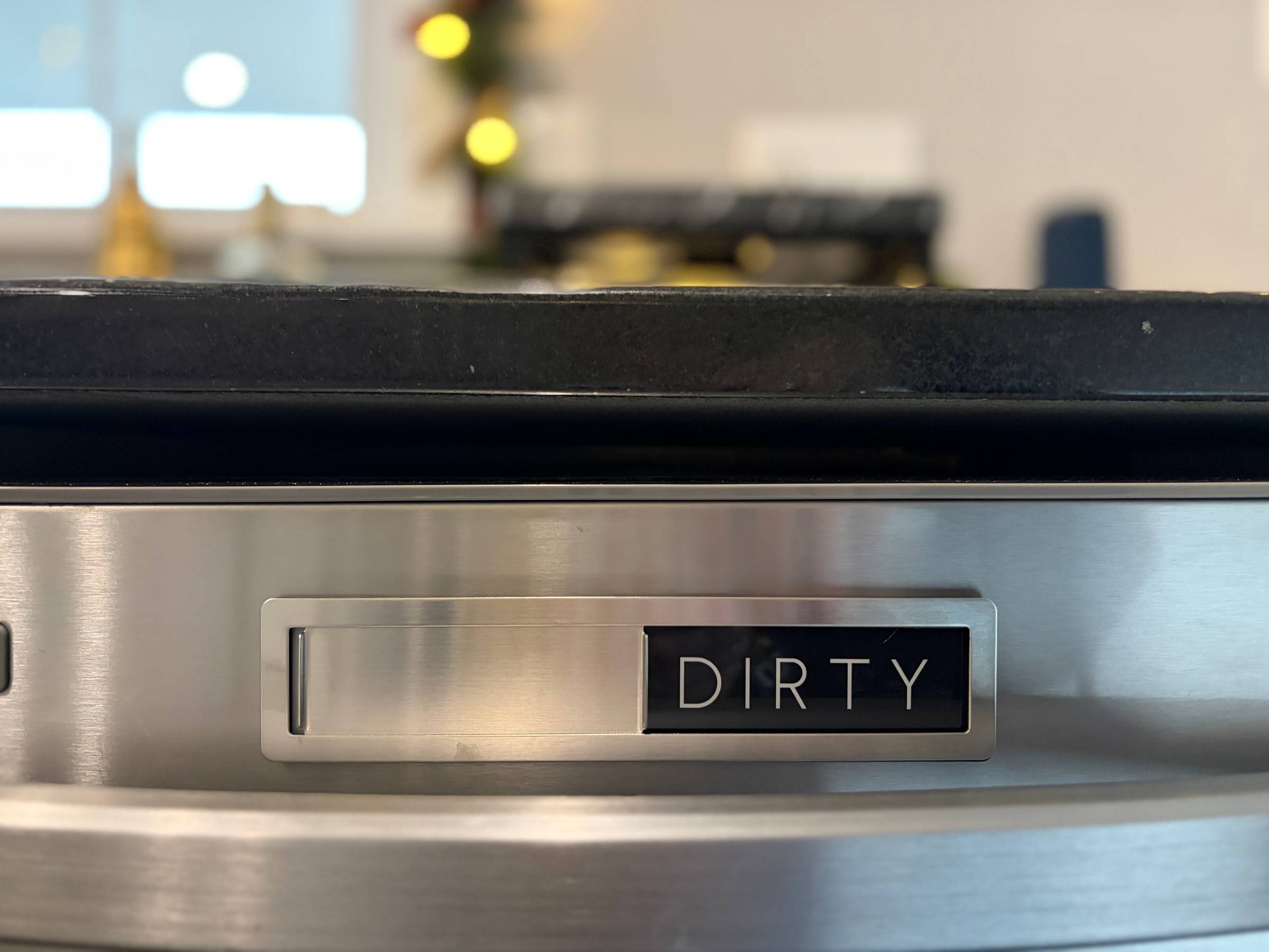 A magnetic dirty sign hangs on a dishwasher
