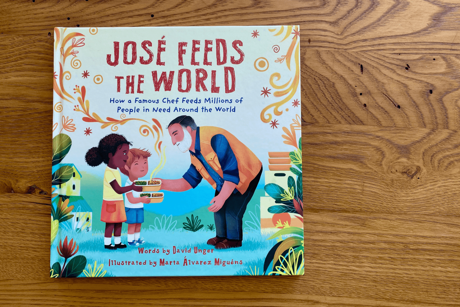 The children’s picture book “Jose Feeds the World” sits on a wooden table