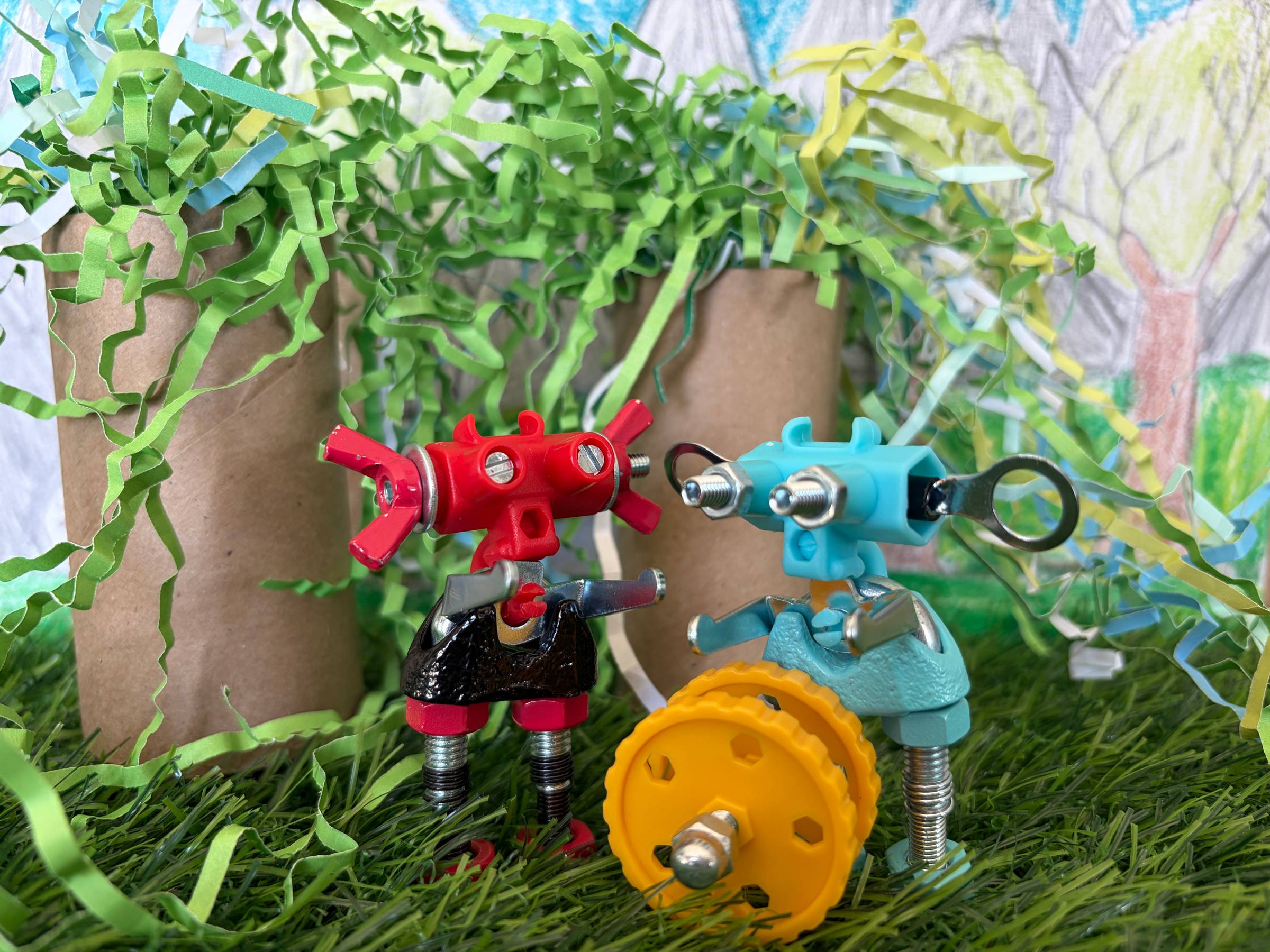 Two OffBits characters stand in front of trees made from cardboard tubes