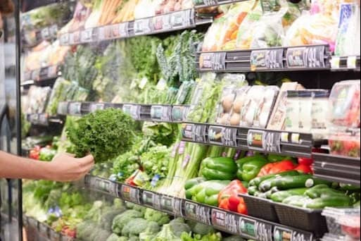 male browsing fresh produce at store with DoorDash bag