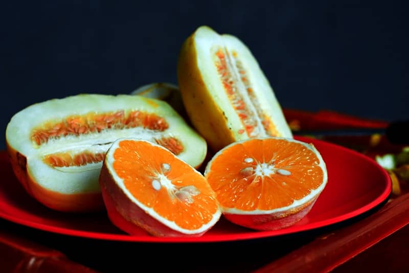 A red plate topped with sliced oranges on top of a table