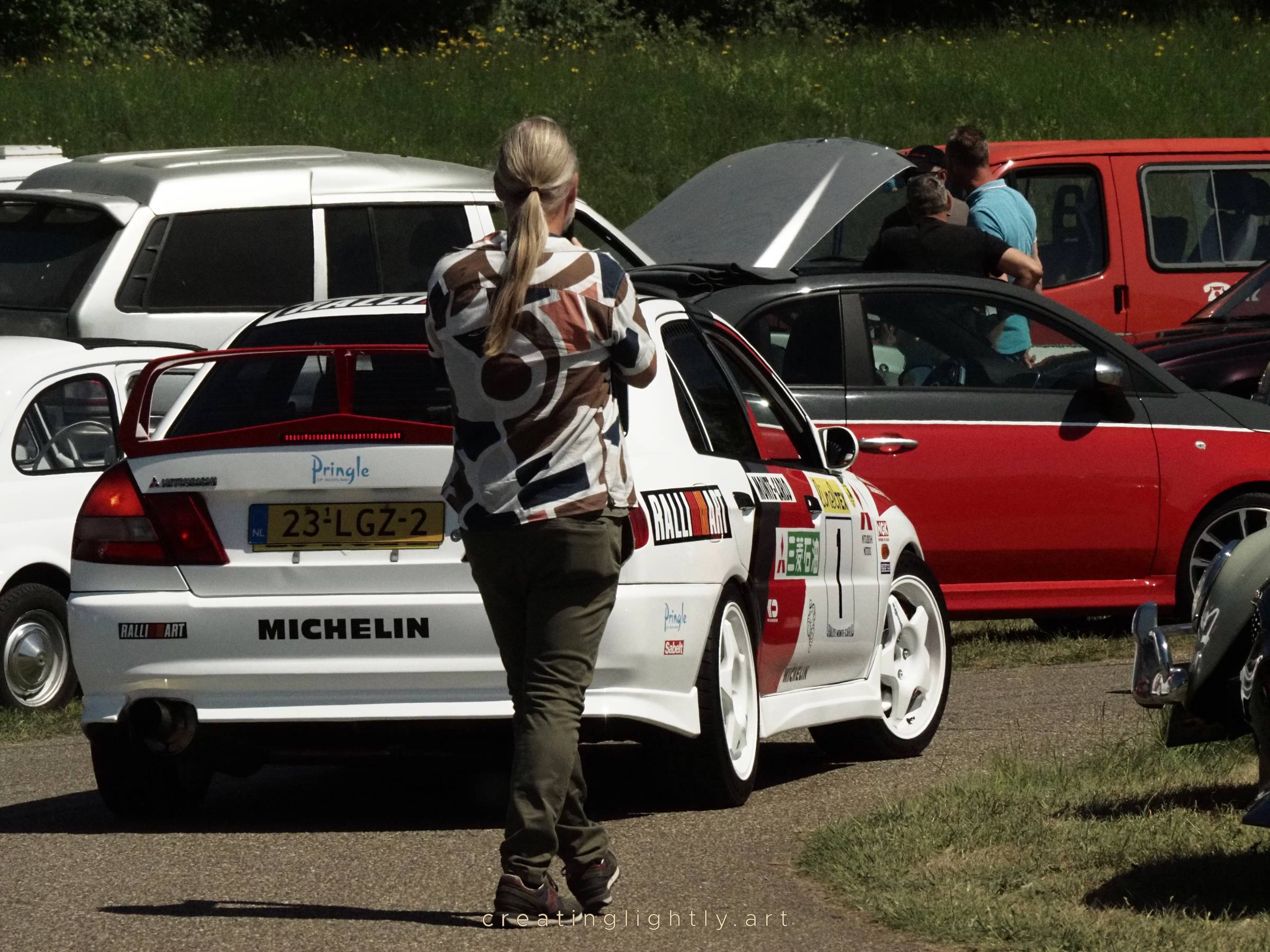 Woman taking a picture of a Mitsubishi Lancer with rally livery at a car event