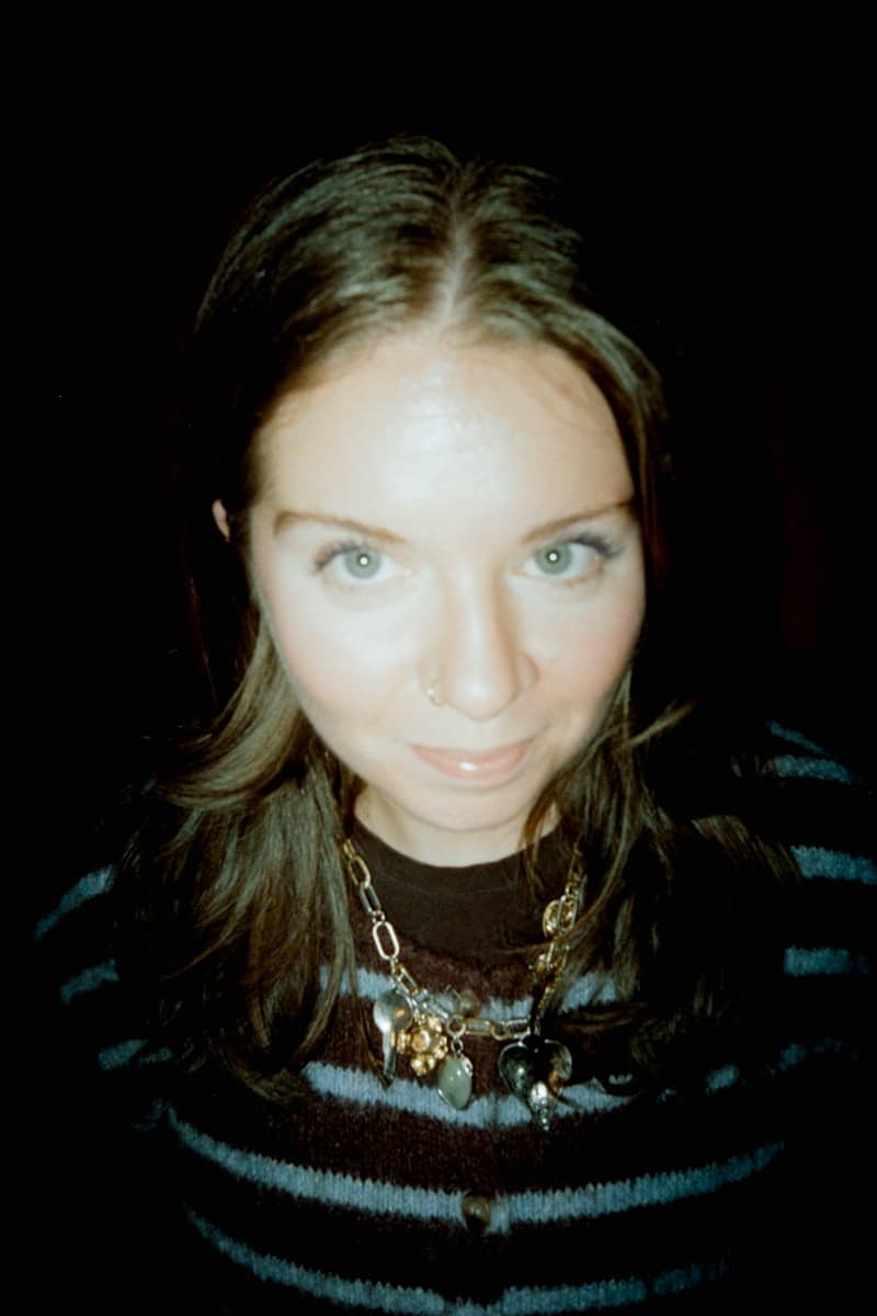 A woman with blue eyes and a striped sweater