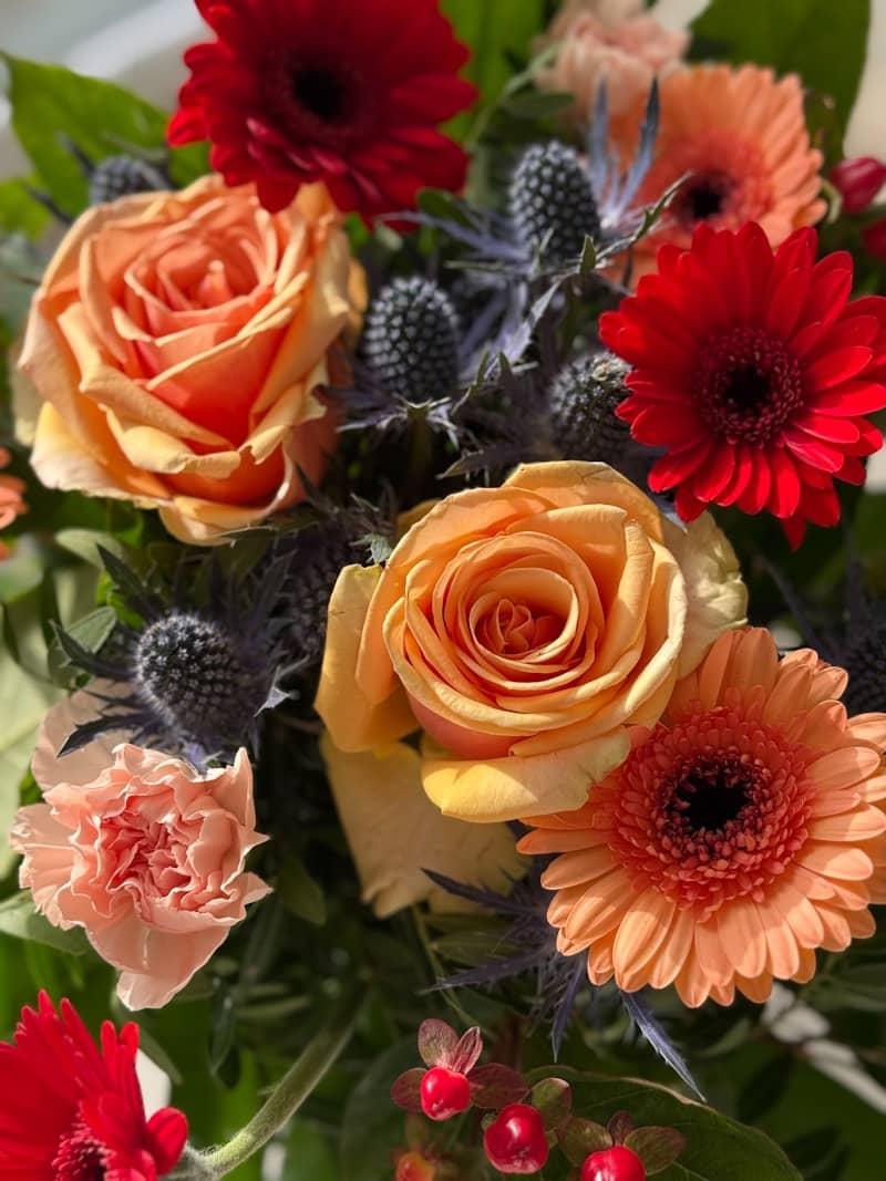 A vibrant bouquet of roses, gerbera daisies, and thistles.