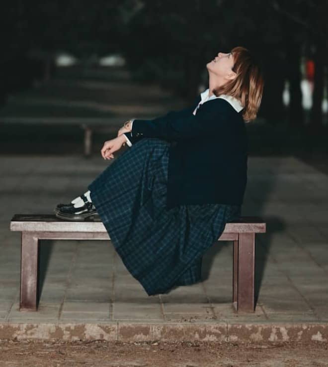 Woman sitting on bench looking up at night