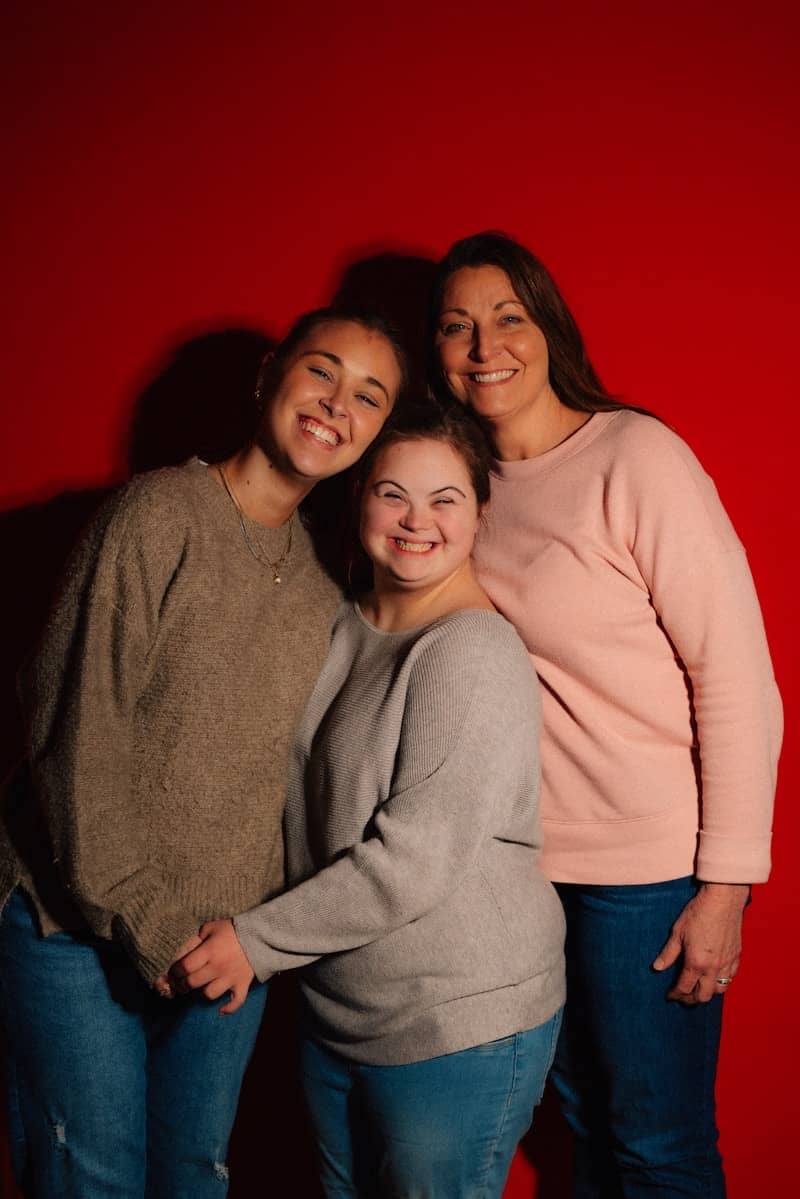 Three smiling women pose against a red background.