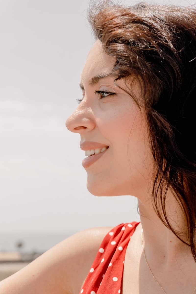 Profile of a smiling woman with dark hair wearing a red polka dot dress