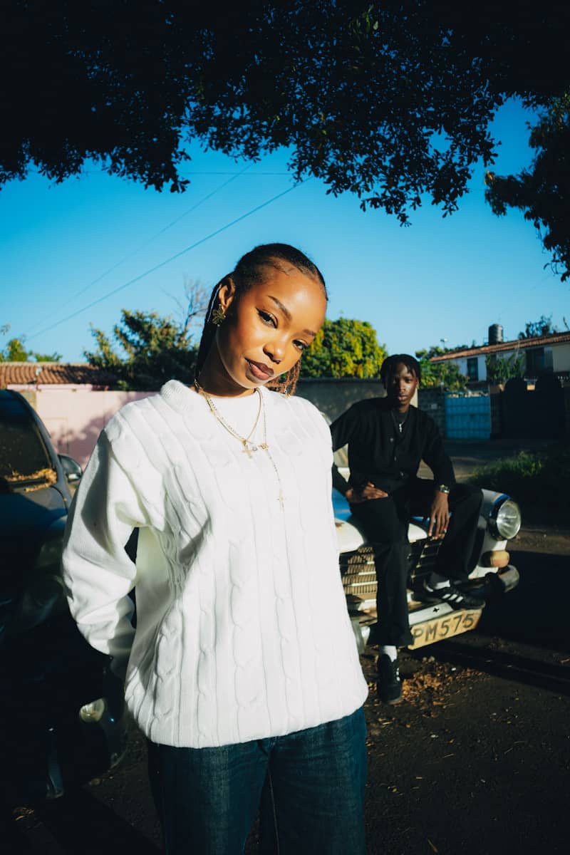 Two young people posing near a vintage car outdoors.