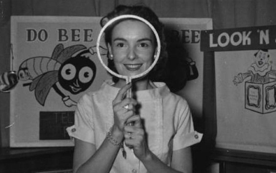 Woman holding what looks like a round mirror but it doesn't have glass, so you can see her face.