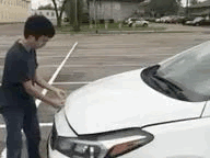 Young man opening the bonnet of a car