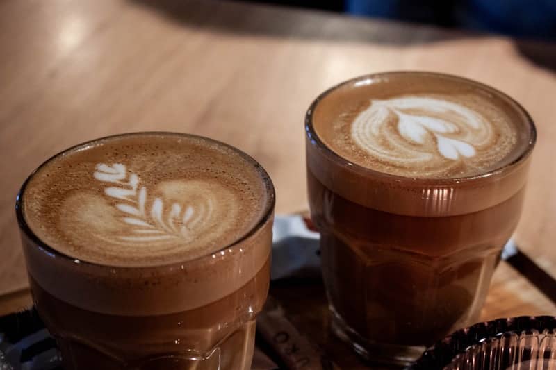 Two cups of coffee sitting on top of a wooden table