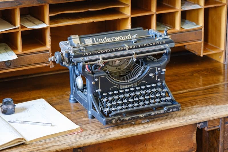 Vintage underwood typewriter on a wooden desk with a ledger.