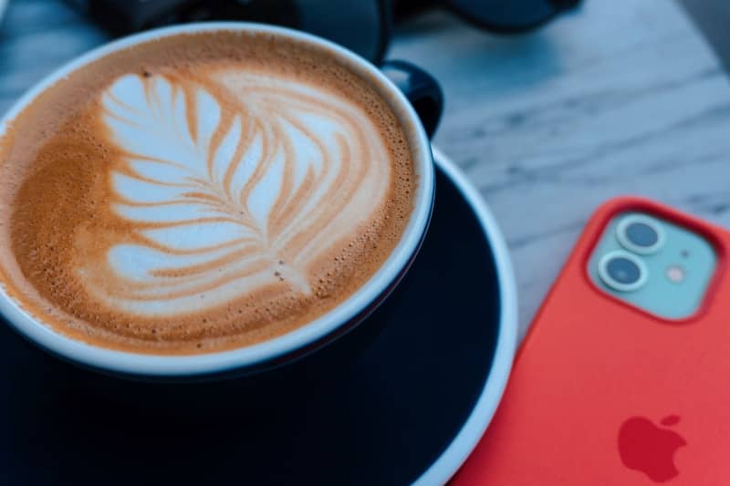 Cup of coffee with latte art next to phone