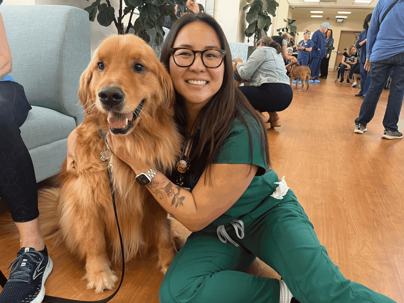 Di Pham, RN, BSN, pictured next to a golden retriever dog.
