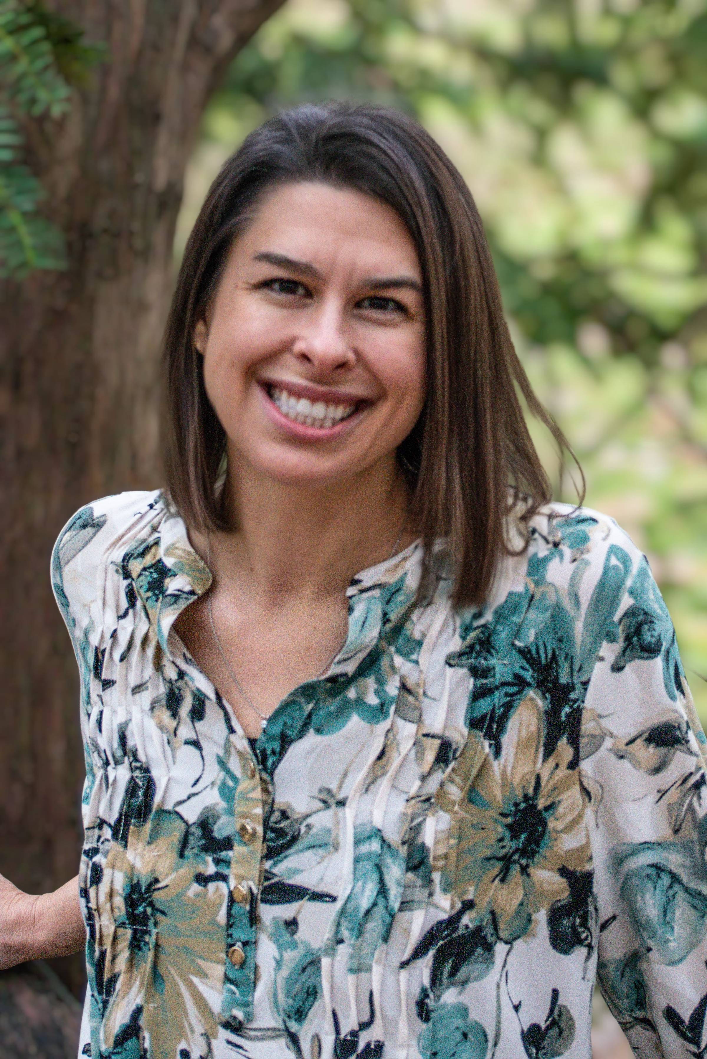 Kate Buckley is seen posing next to a tree and smiling.