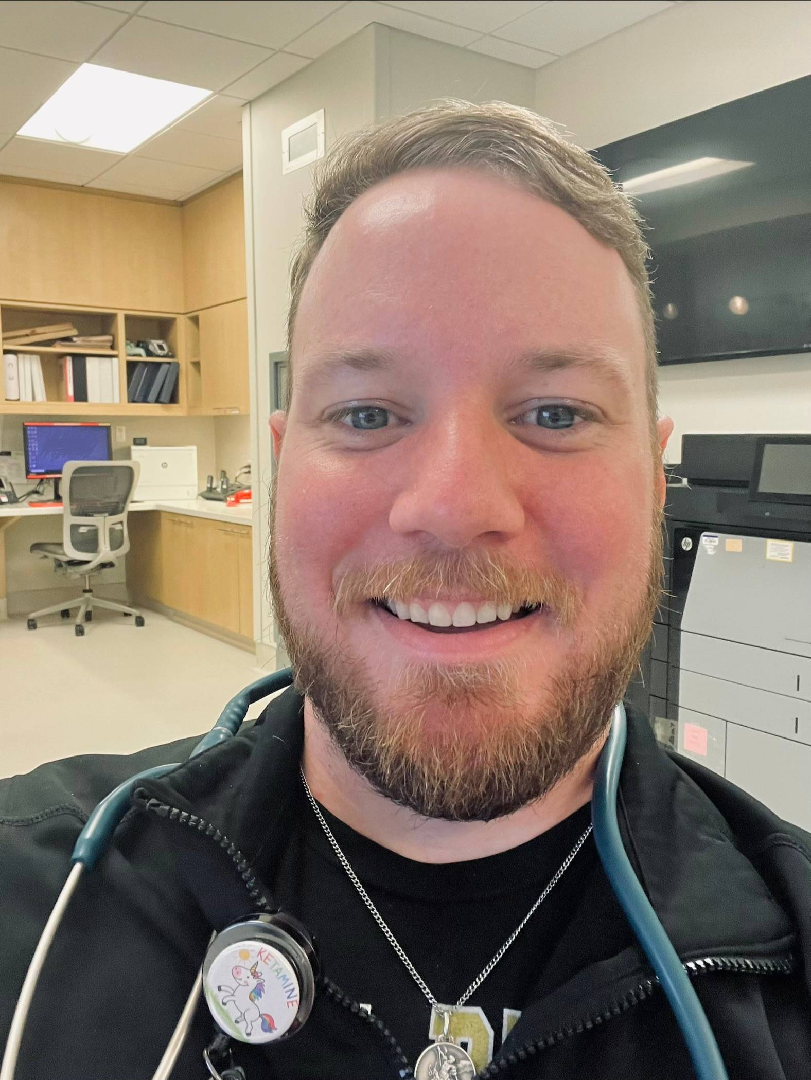 Nic Ewbank, RN, BSN, EMT-P, smiles while wearing scrubs at the hospital.