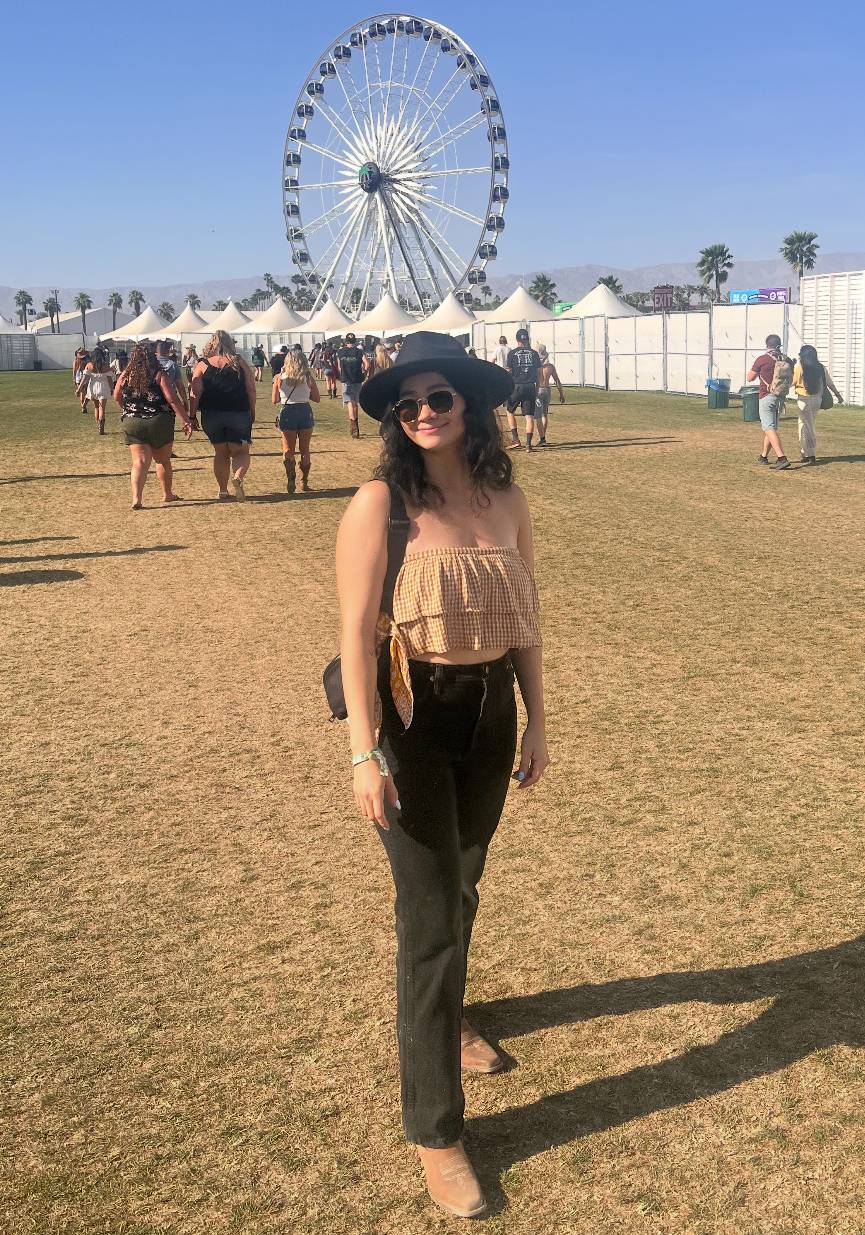 Person standing on grass wearing a hat and sunglasses