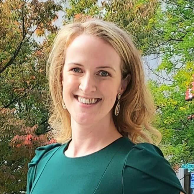 Nurse Anne Denk is pictured smiling while standing in front of trees.
