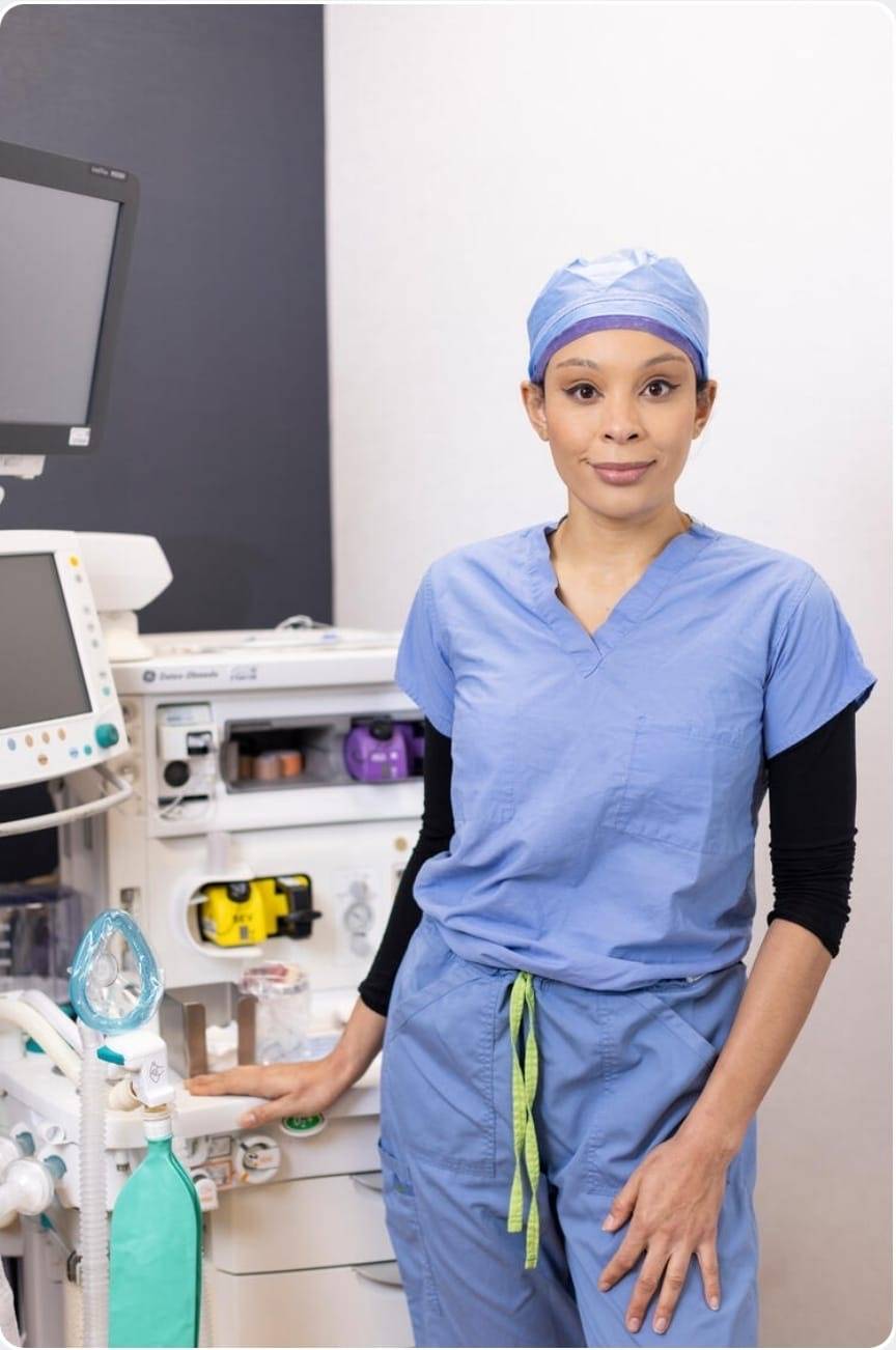 Nuzhet Meridew, DNAP, CRNA, APRN, stands in a hospital room wearing scrubs.