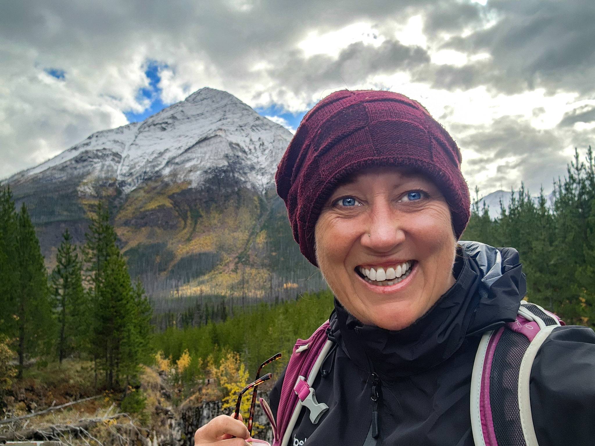 Nurse Anita Lambert smiles in front of a mountain landscape while hiking.