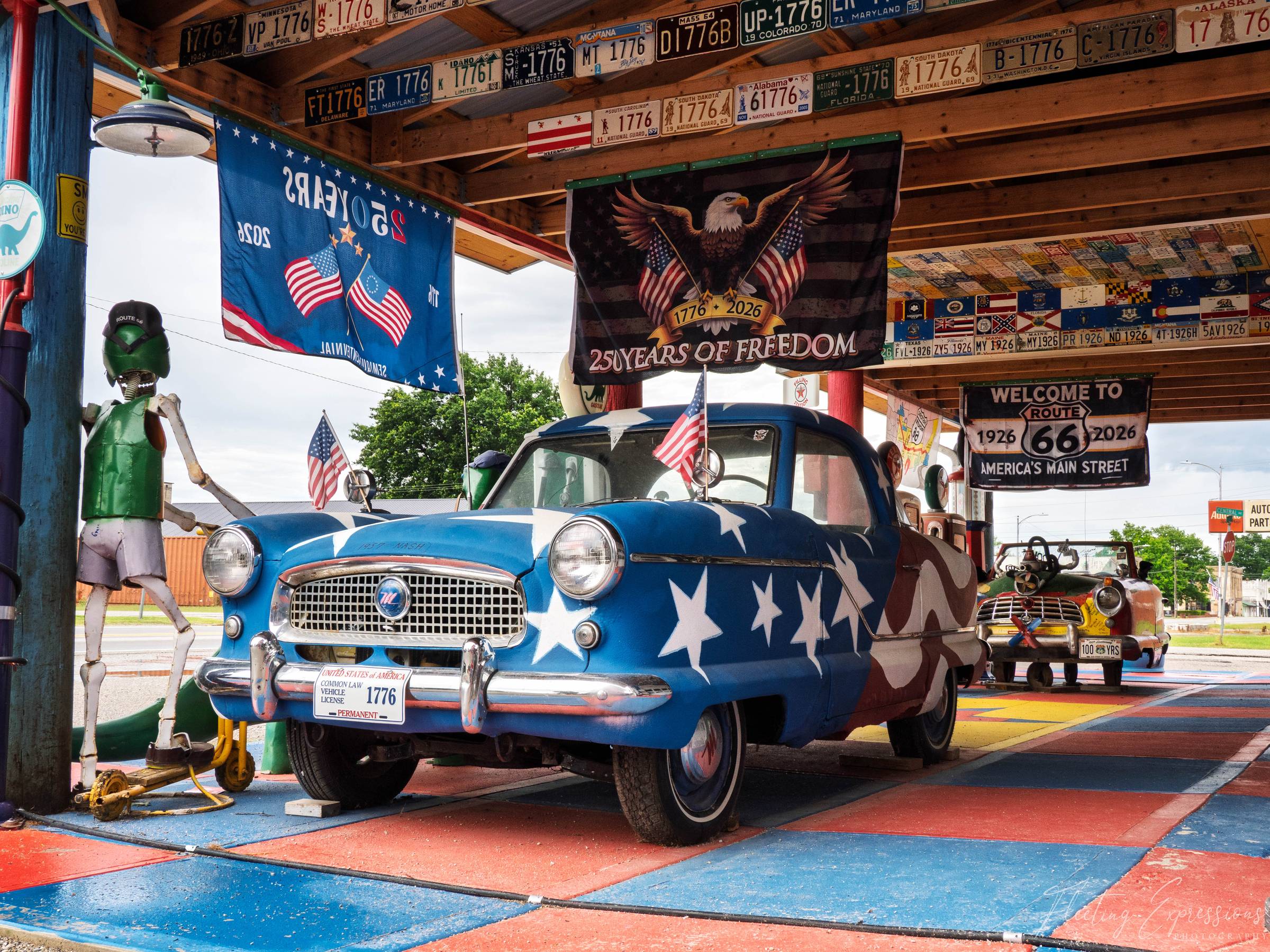 A blue Nash painted with white stars sits under license plates reading 1776 and flags marking 250 years of freedom.