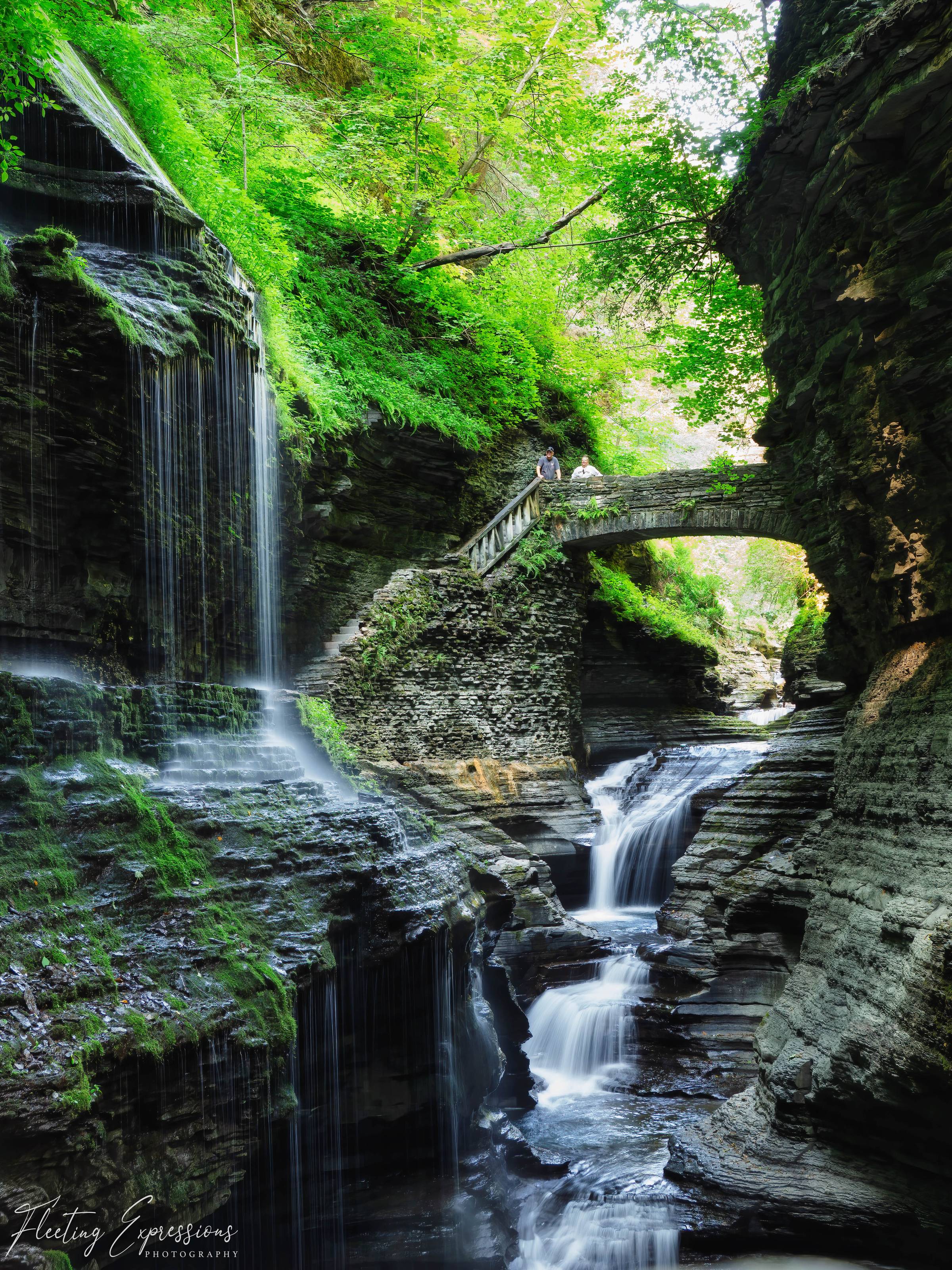 Waterfall flowing under a stone bridge