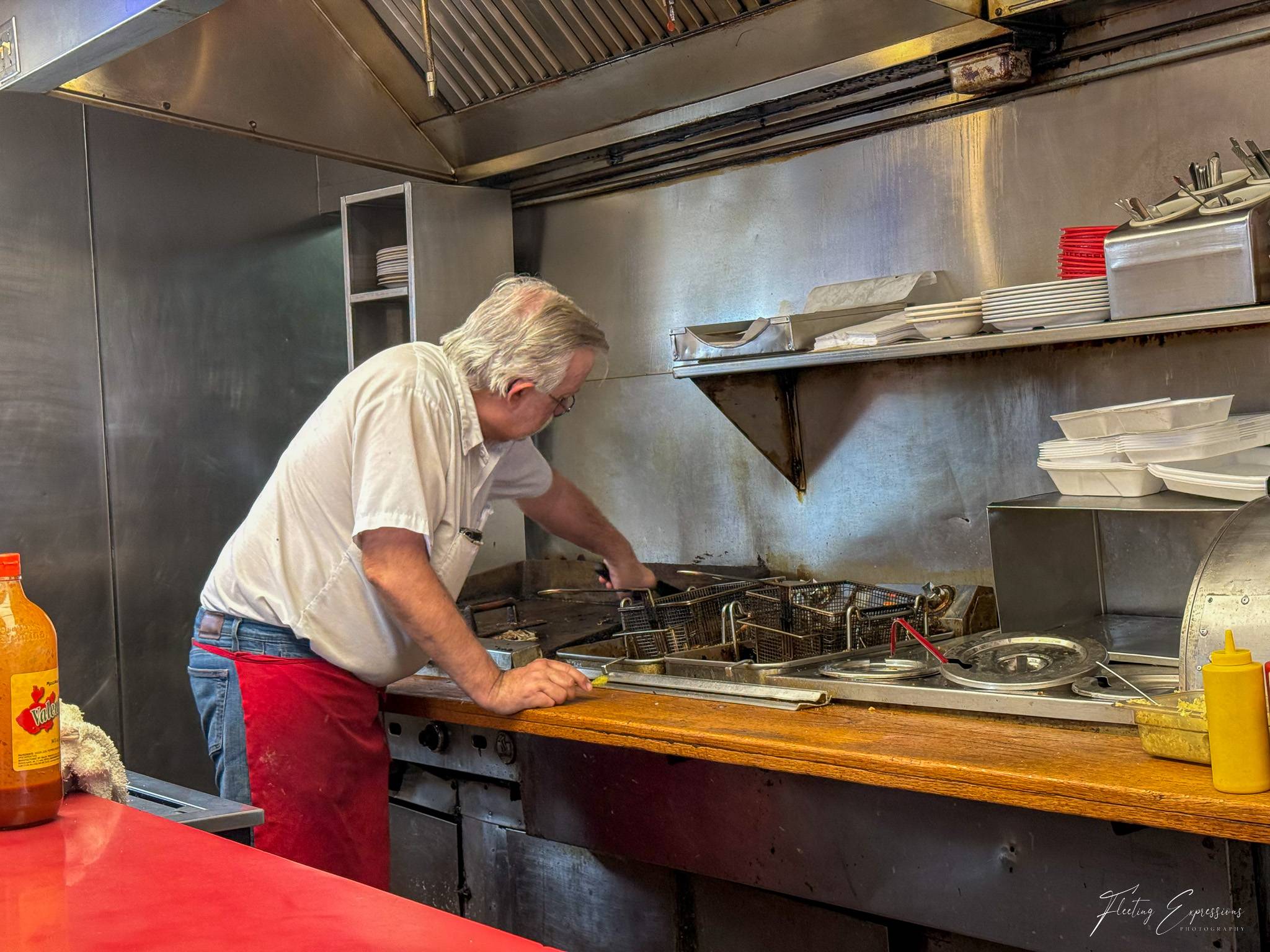 A man in a white shirt and red apron works over a commercial grill at Roberts Grill in El Reno, Oklahoma, a Route 66 institution open since 1926.