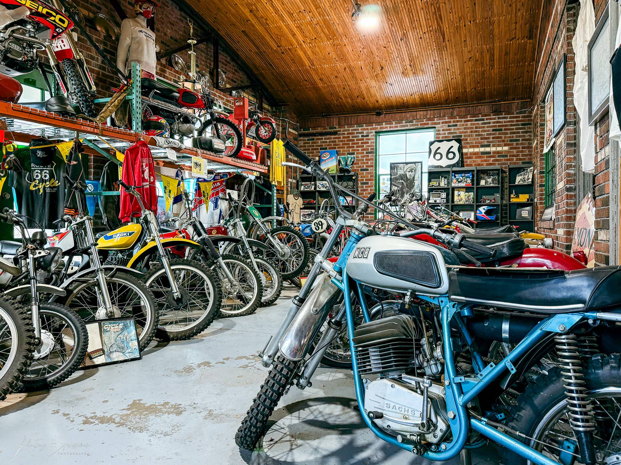 Rows of vintage motorcycles of all sizes and colors fill the interior of the Seaba Station Motorcycle Museum, with racing jerseys, Route 66 memorabilia, and signage covering the brick walls and wooden ceiling.
