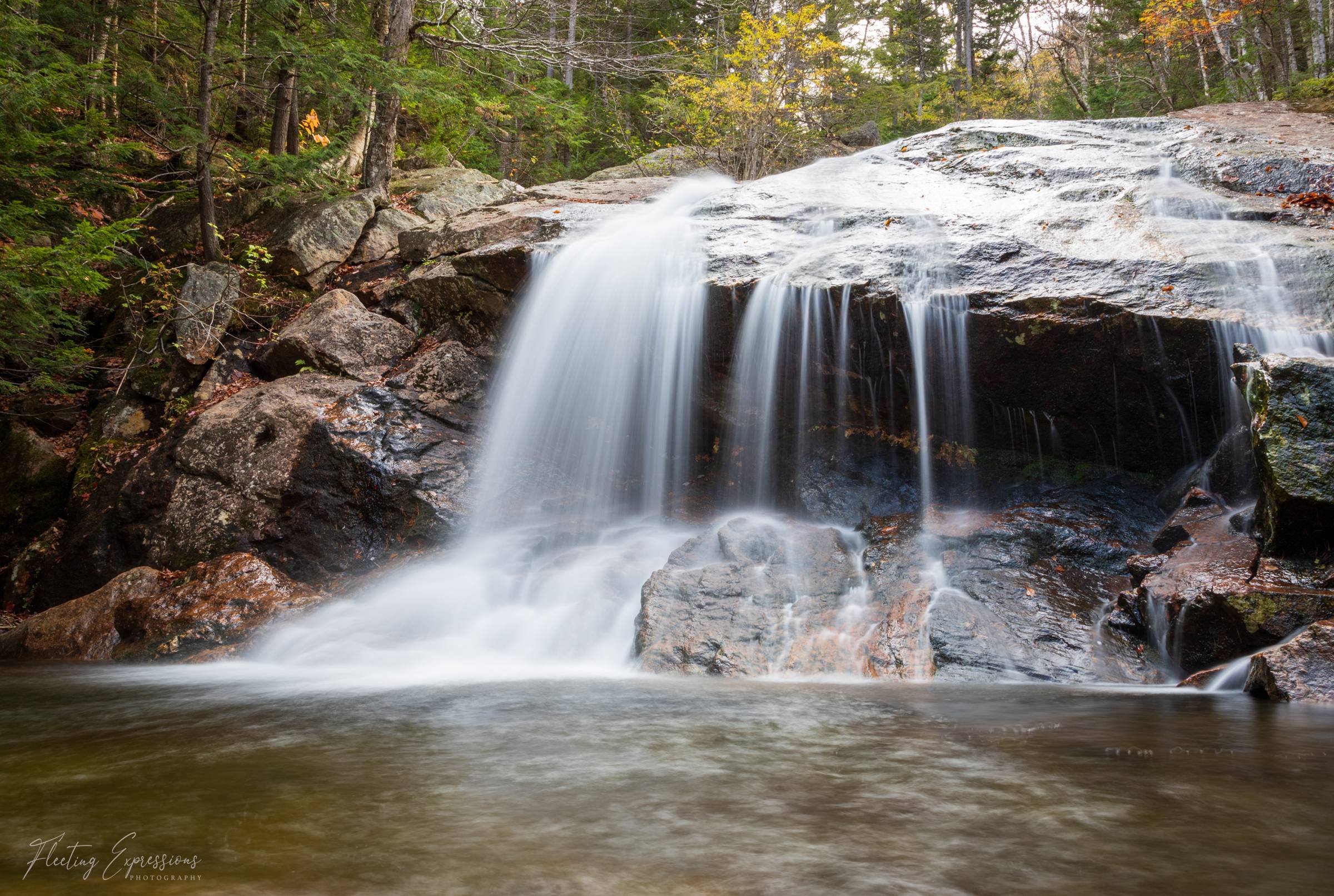 Waterfall in rocky landscape with greenery in background