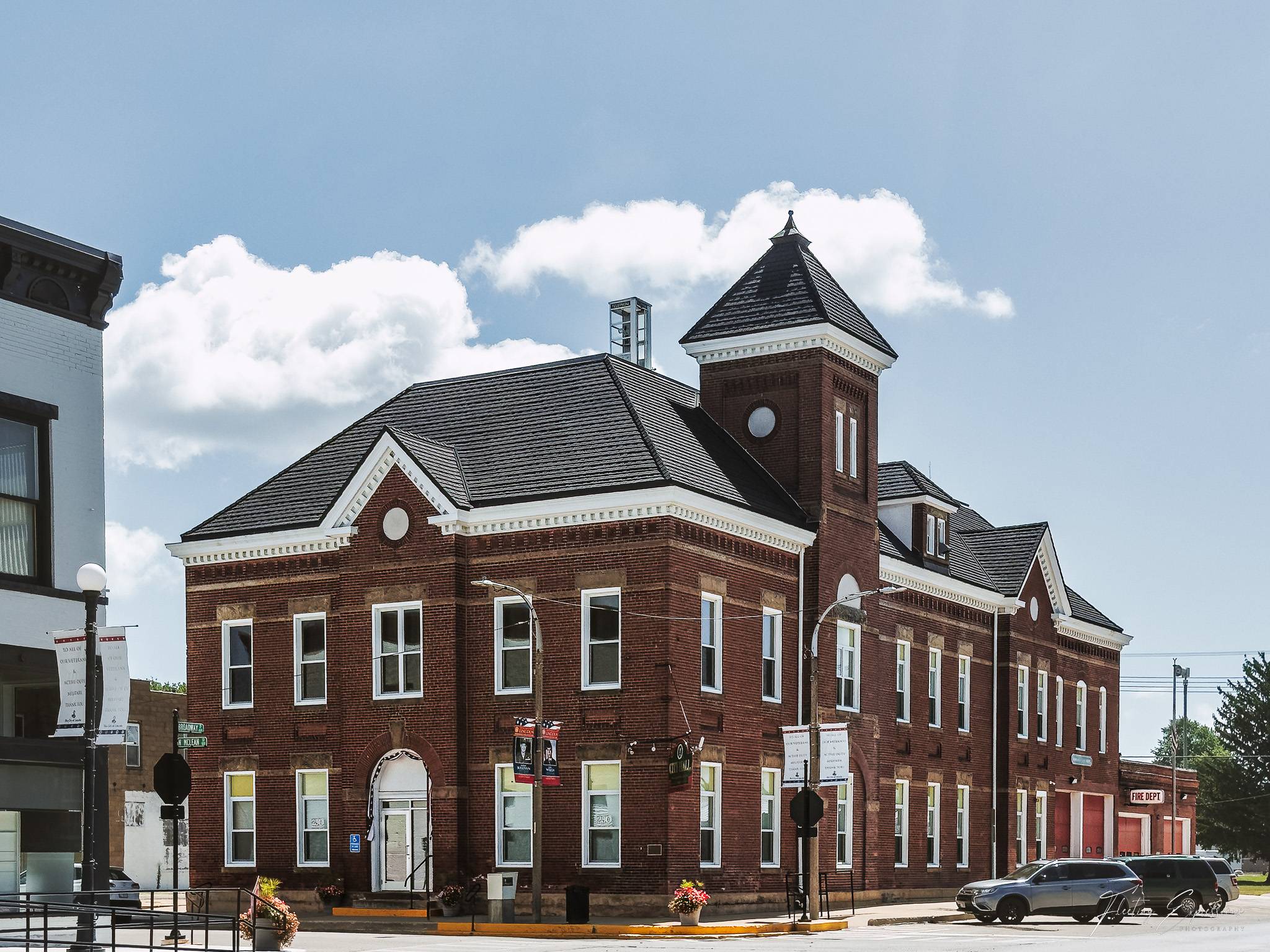 A brick fire station in Lincoln, Illinois, with a Fire Dept sign by the door and a small phone booth on its rooftop tower.