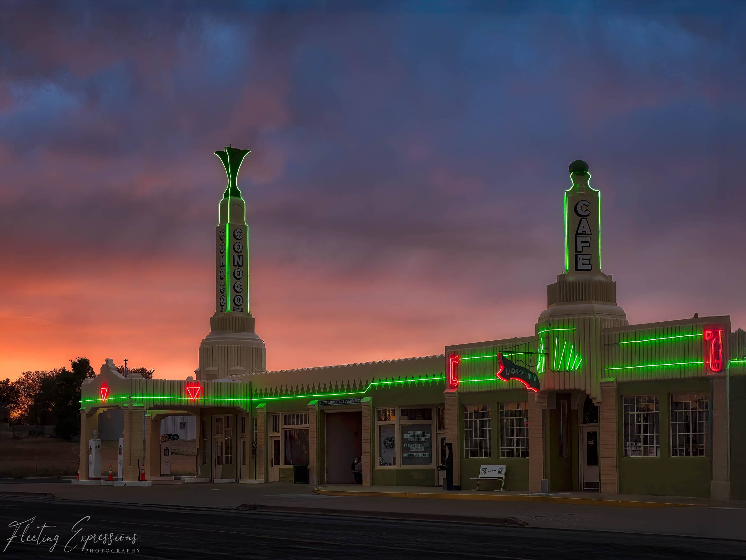 The U-Drop Inn in Shamrock, Texas at dusk, with green neon lights glowing against a dramatic orange and purple sunset sky.