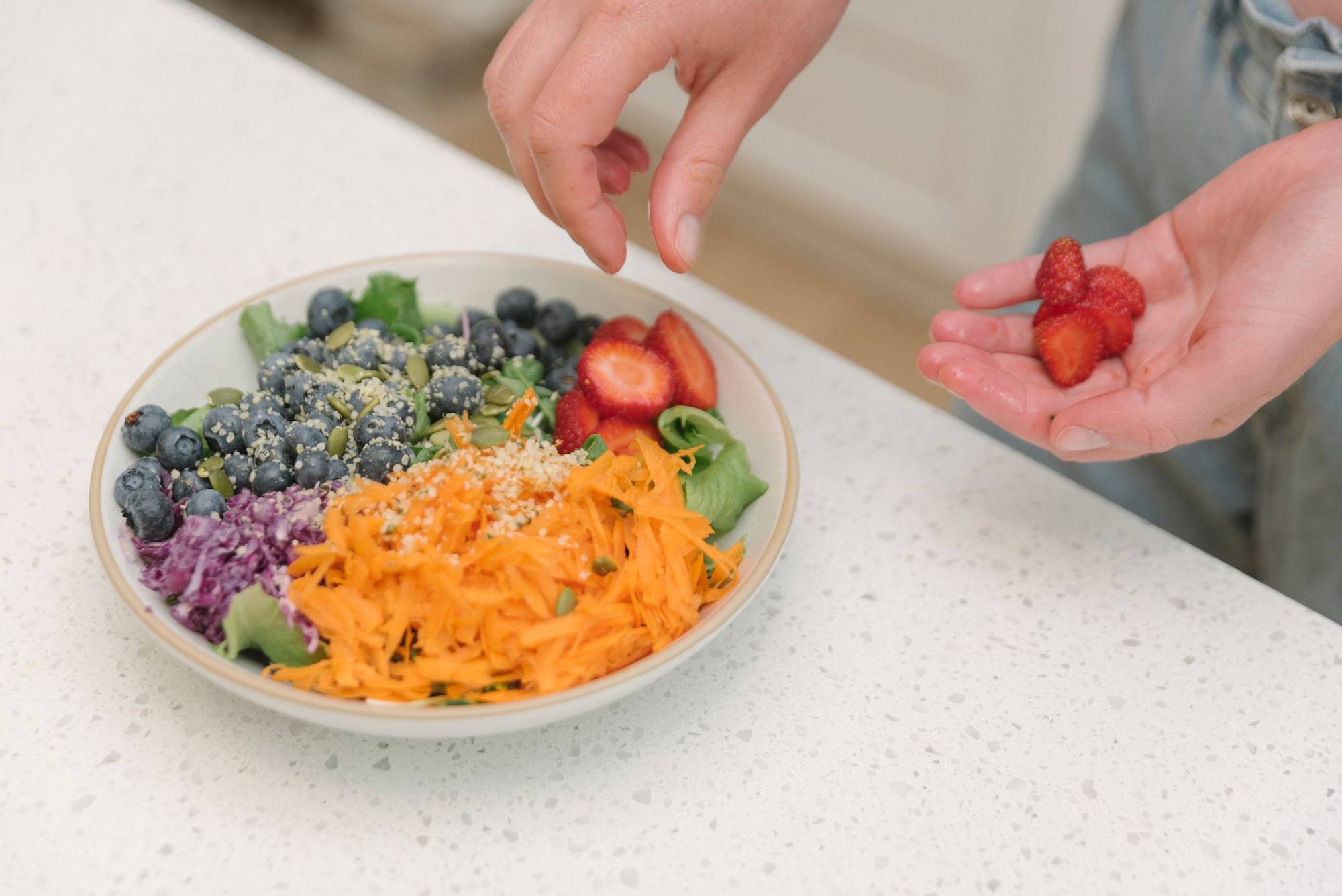 a bowl filled with vegetables and dressing next to a glass of milk