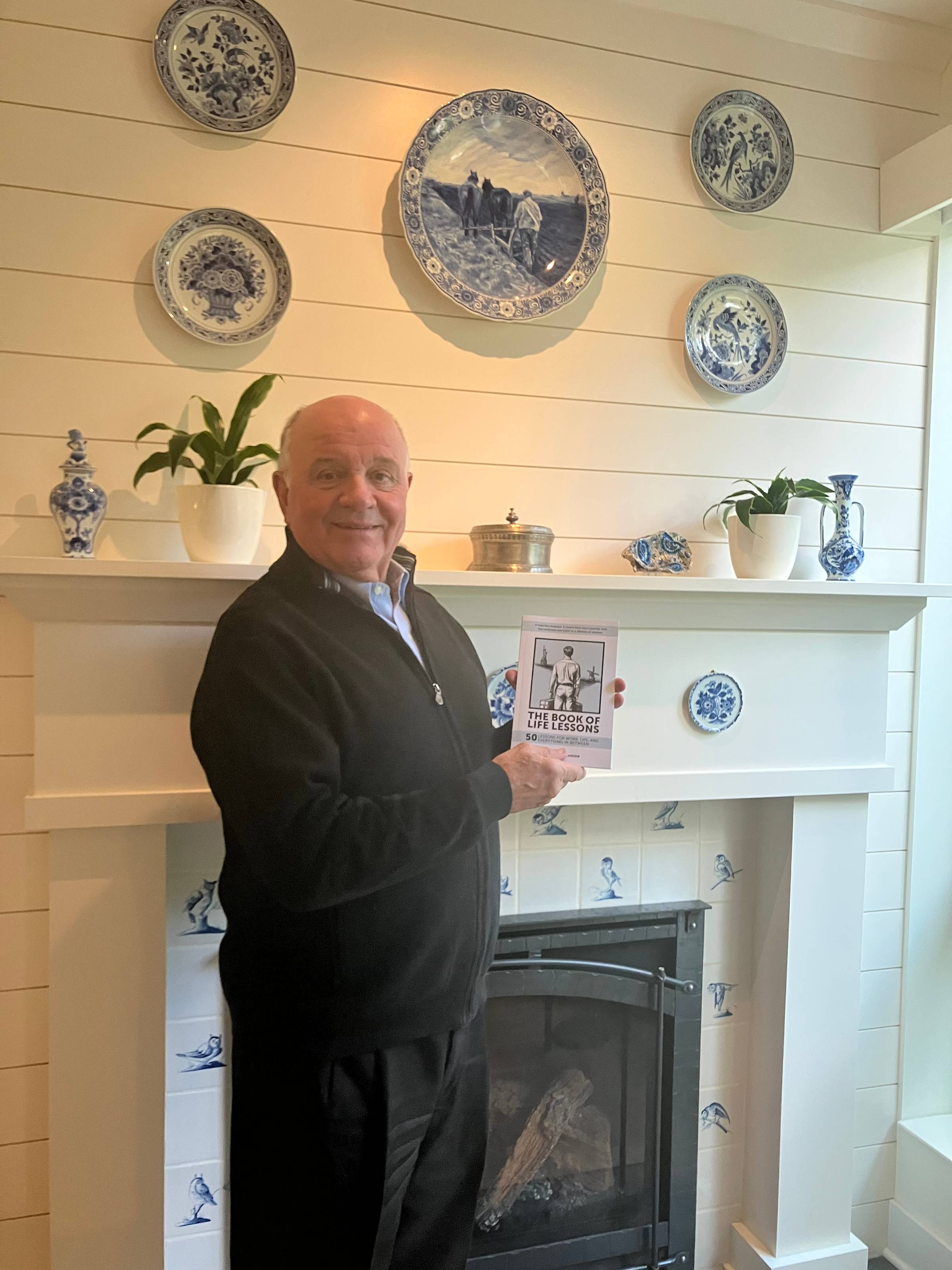 Louis Slangen holds a copy of his book in front of a fireplace