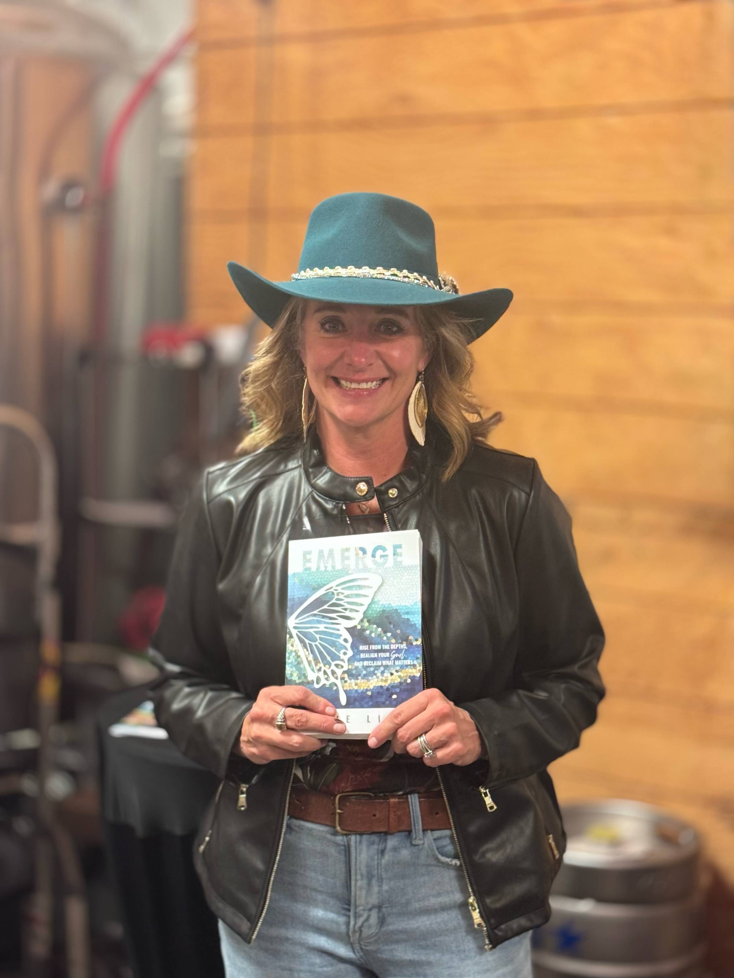 Angie Lion, author of Emerge, holds a copy of her book