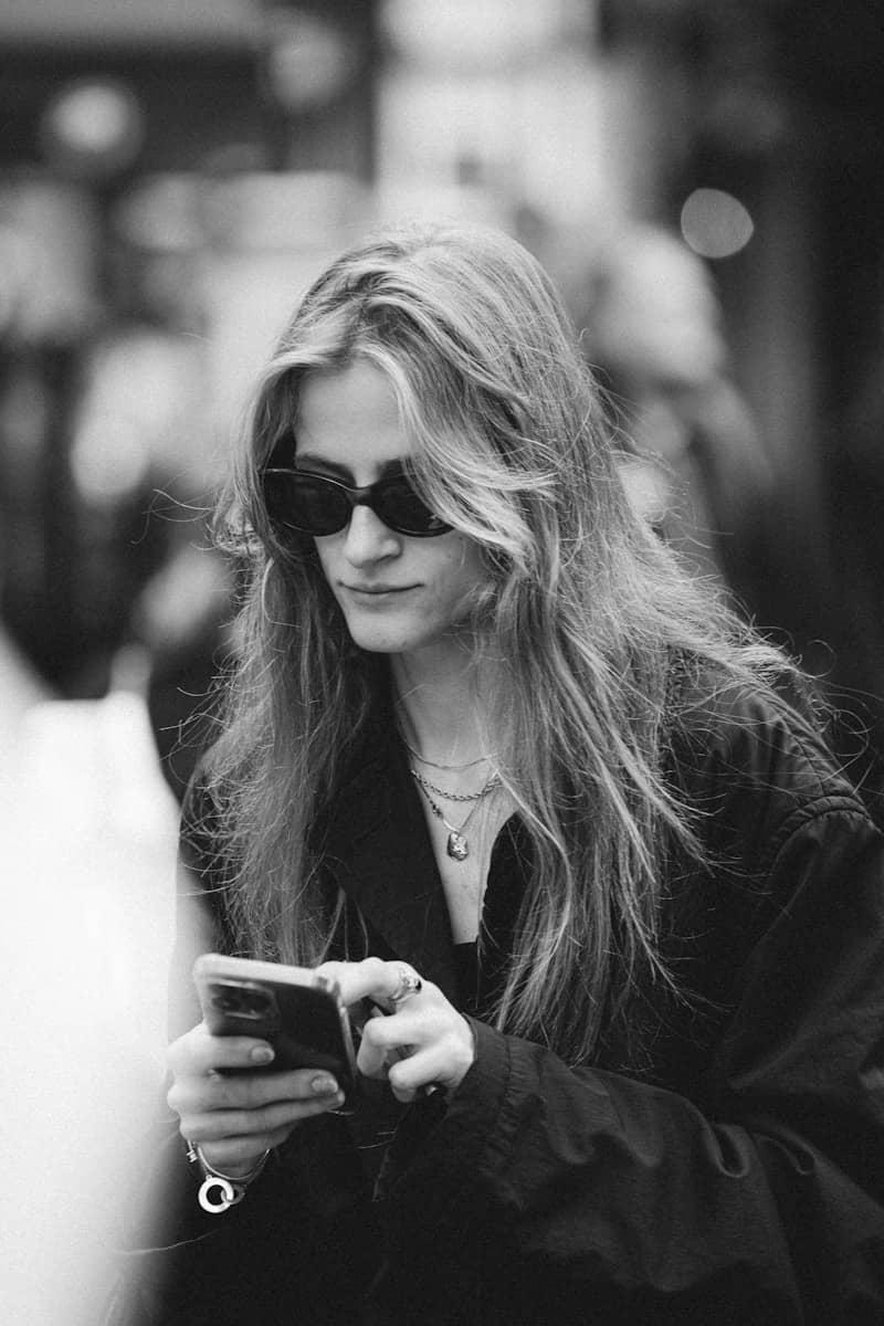 A woman with long hair wearing sunglasses using a smartphone in Amsterdam