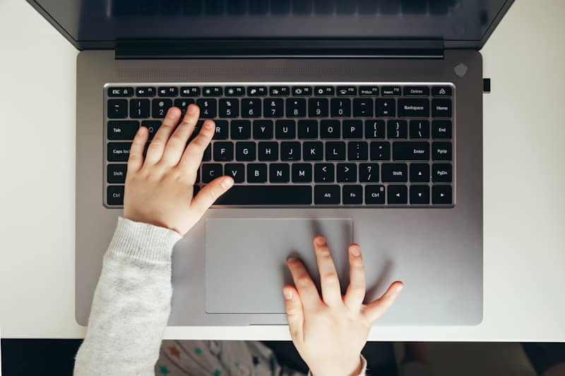 Child's hands typing on a laptop keyboard