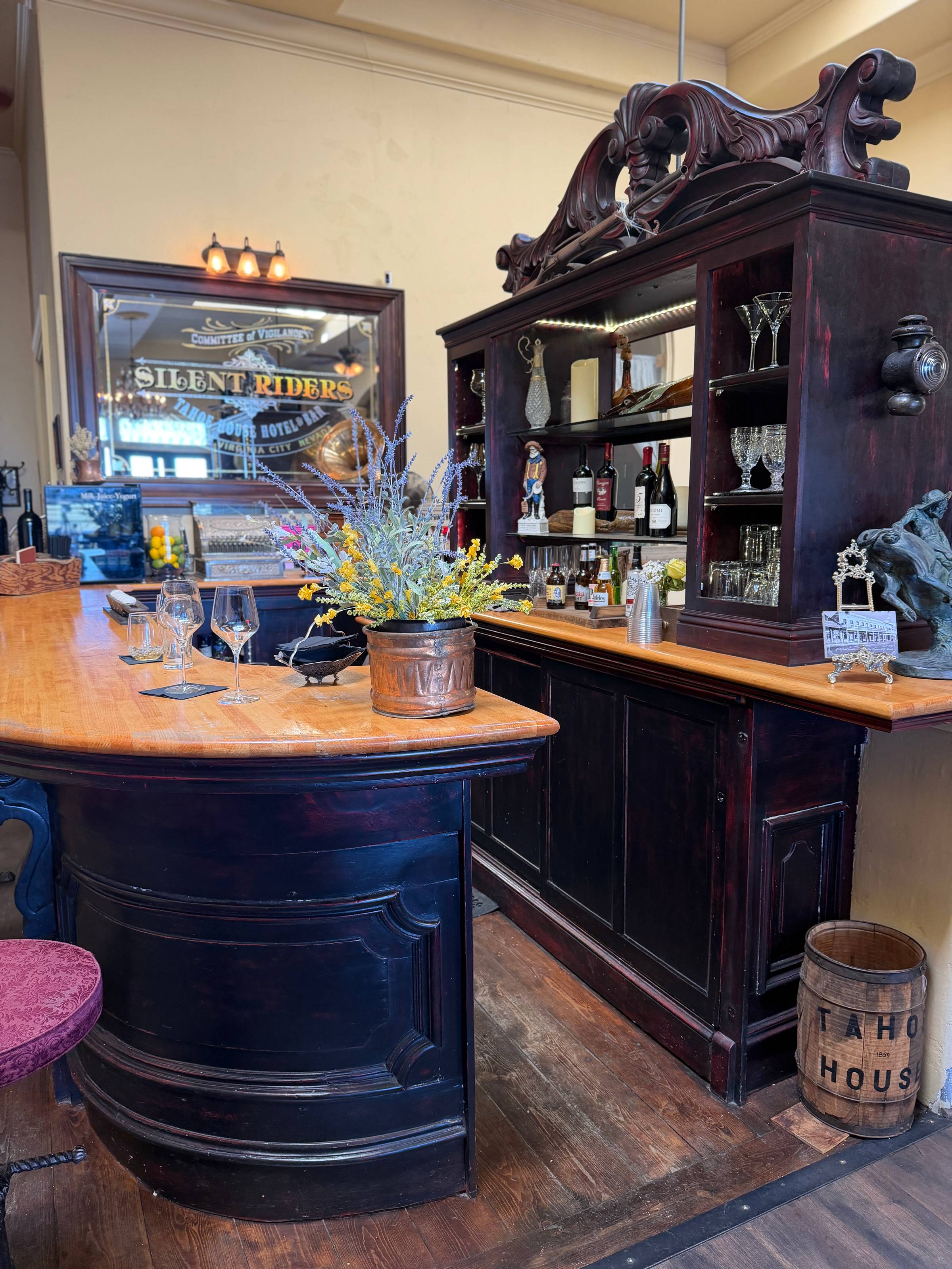 The historic bar at Tahoe House Hotel, Virginia City Nevada — empty glasses on the counter, Silent Riders mirror behind, Tahoe House barrel in the corner.
