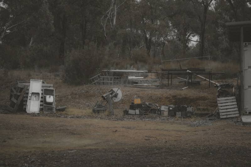 Abandoned equipment sits in a field near trees.