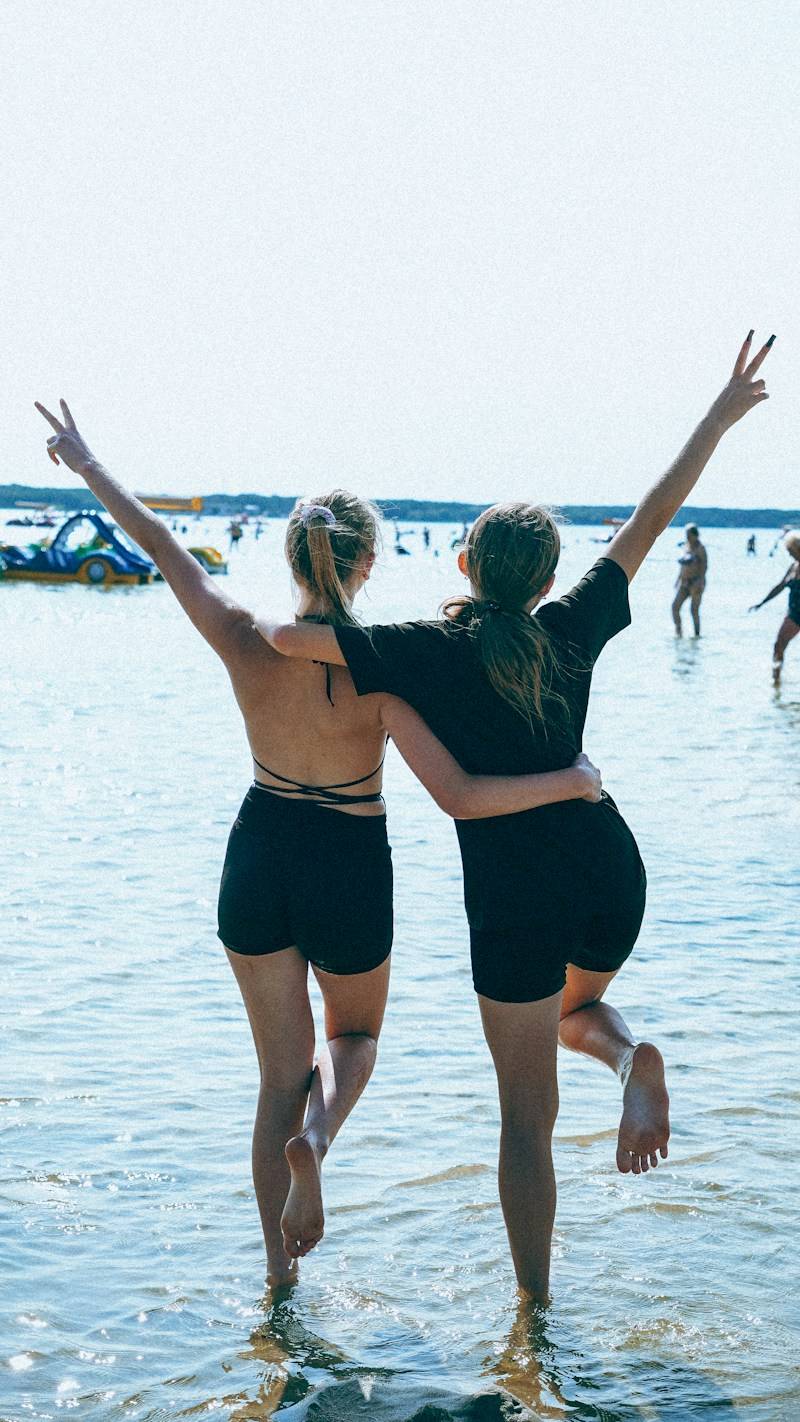 Two young women making peace signs in the water.