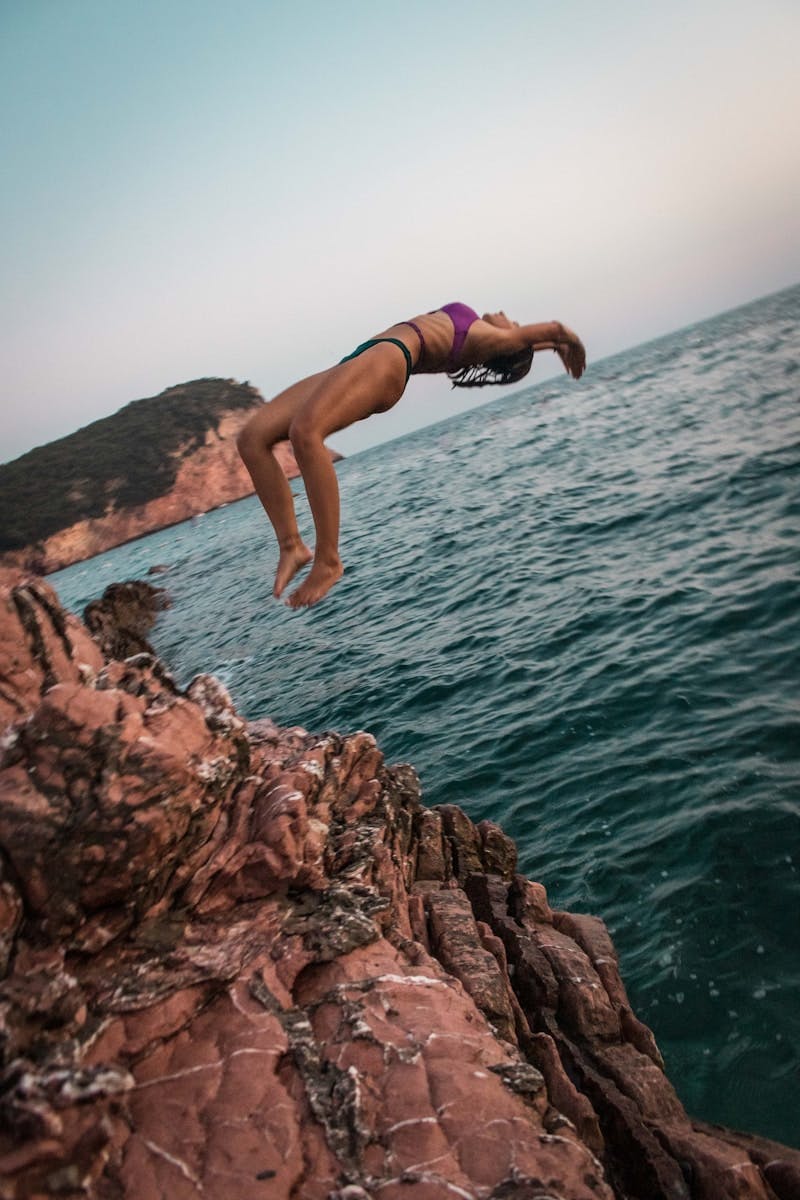 A woman diving off a cliff into the ocean