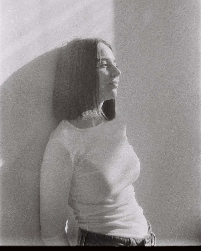 Woman leaning against a wall in soft light