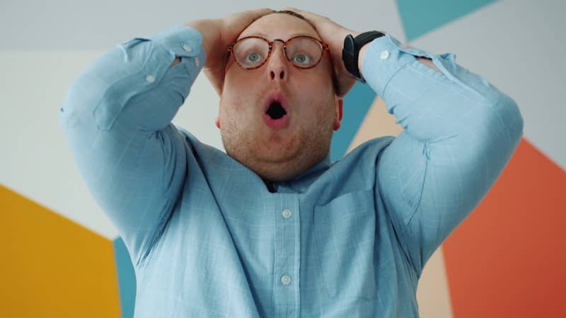 Man with glasses grabs head in shock