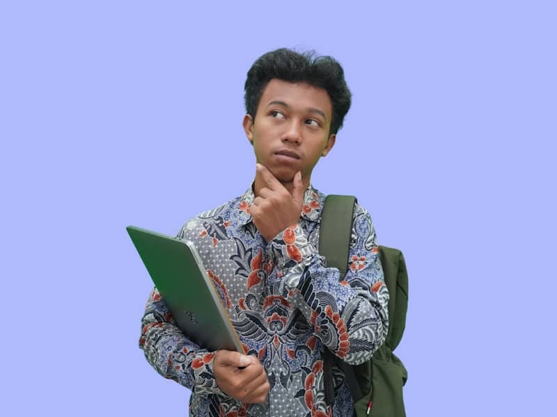 A man with a backpack looking at a laptop