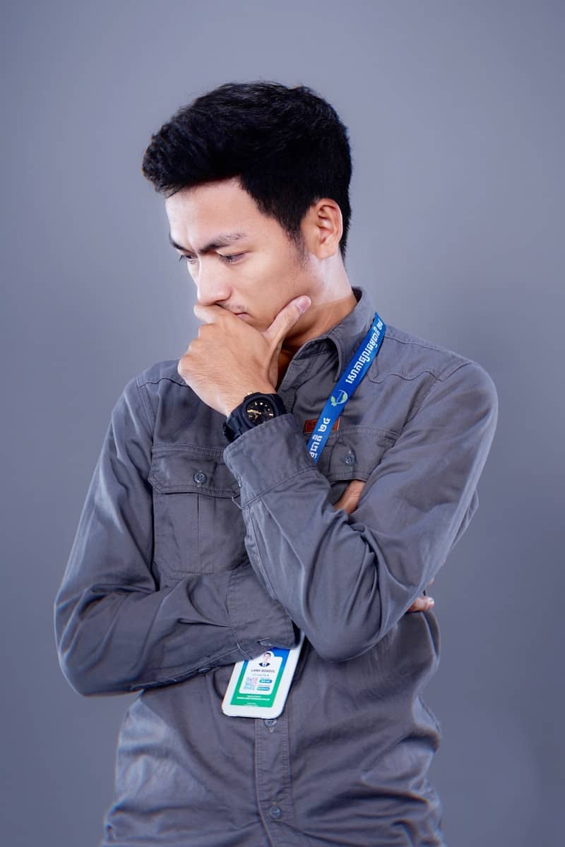 Man in gray shirt thinking with hand on chin