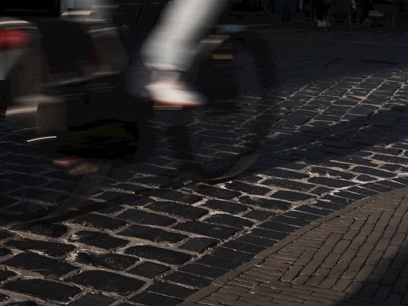 A person rides a bicycle on cobblestone.