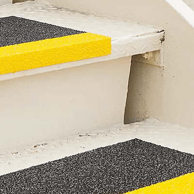 A set of stairs with textured horizontal surfaces and bright yellow lines on their edges