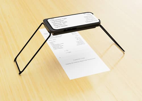 An iPhone in a Case for Vision stand magnifies a printed receipt on a table. The screen shows a clear, high-contrast view of details like total, payment type, and code.