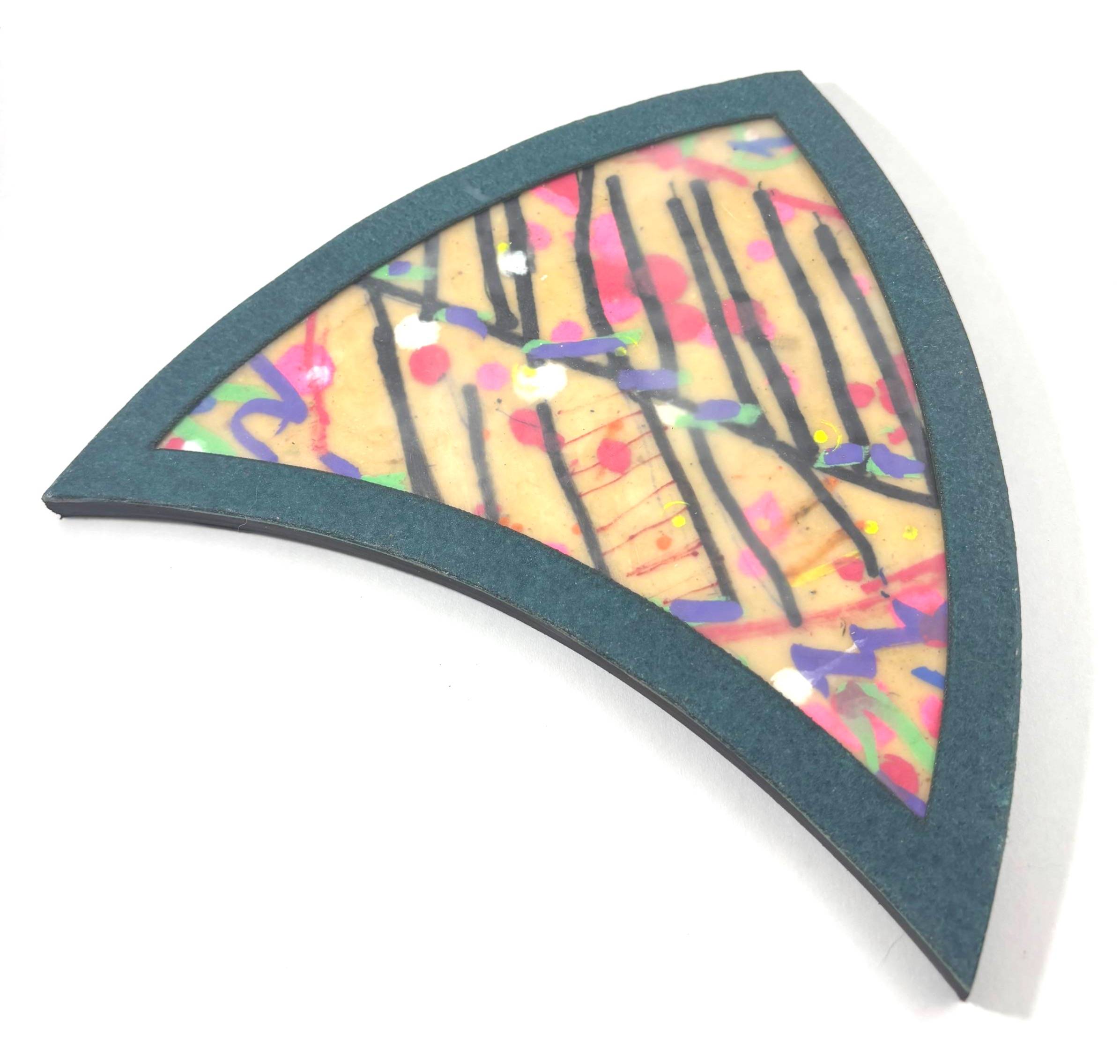A fan-shaped encaustic panel with a dark teal border. Inside, bold black lines cross over warm beige wax embedded with bright marks in pink, purple, yellow, green, and orange — made by a community participant at the AmplifyHER event in Fort Wayne, Indiana
