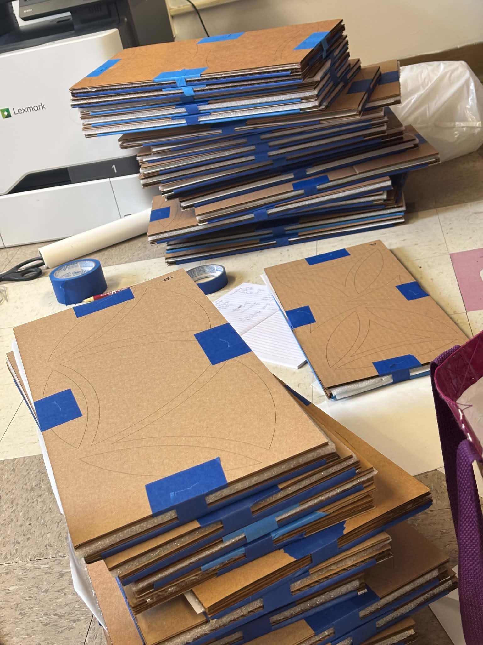 Custom laser-cut cardboard trays stacked and taped, ready to transport 310 Weave of Life panels to ArtPrize 2026.